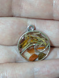 Handmade witchy intention necklace called Tides of Change featuring a spellbound charm with herbs crystals and flowers on a black cord for motivation and energy movement