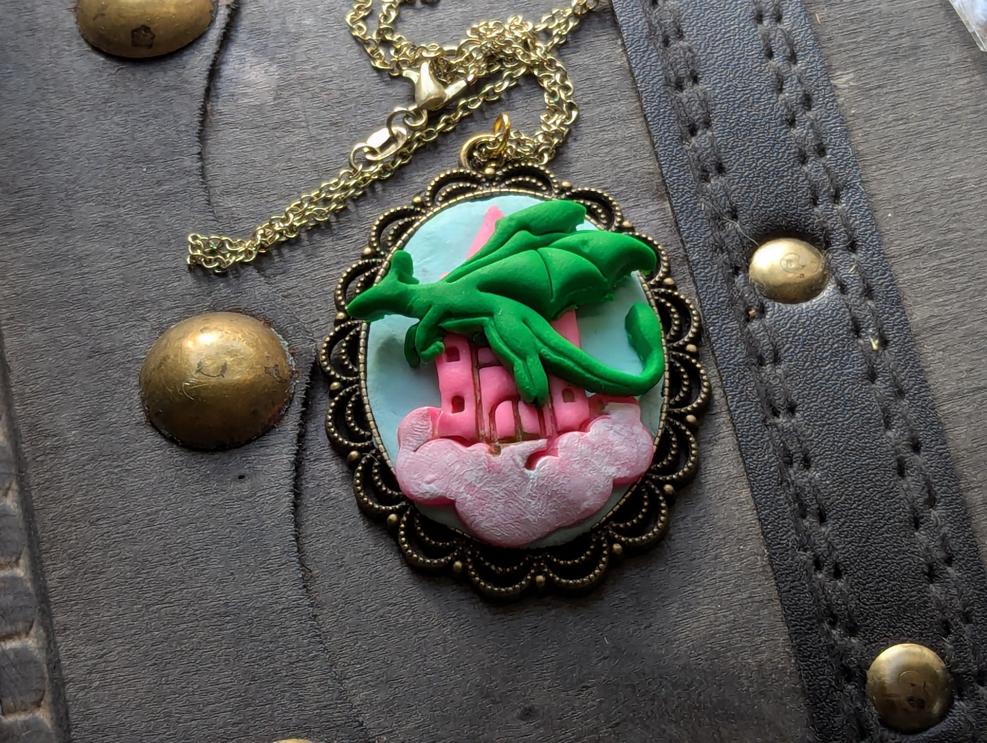 Hand sculpted clay necklace featuring a floating castle and dragon in the sky