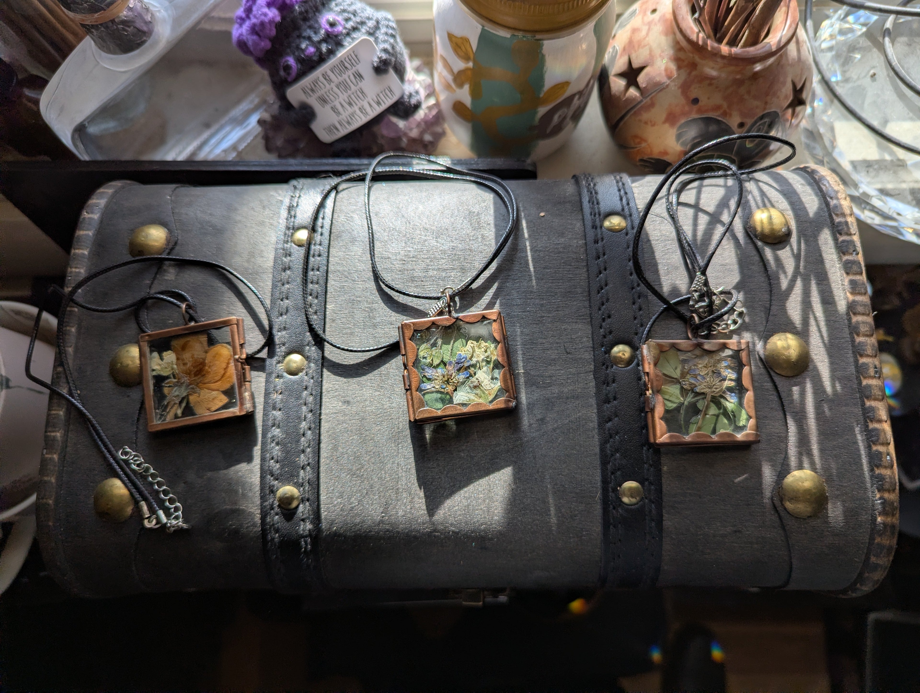 Pressed flower locket necklace on black cord with botanical resin design